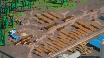 Aerial overview of organized lumber yard with systematically stacked logs, processing equipment, and forest clearing operations